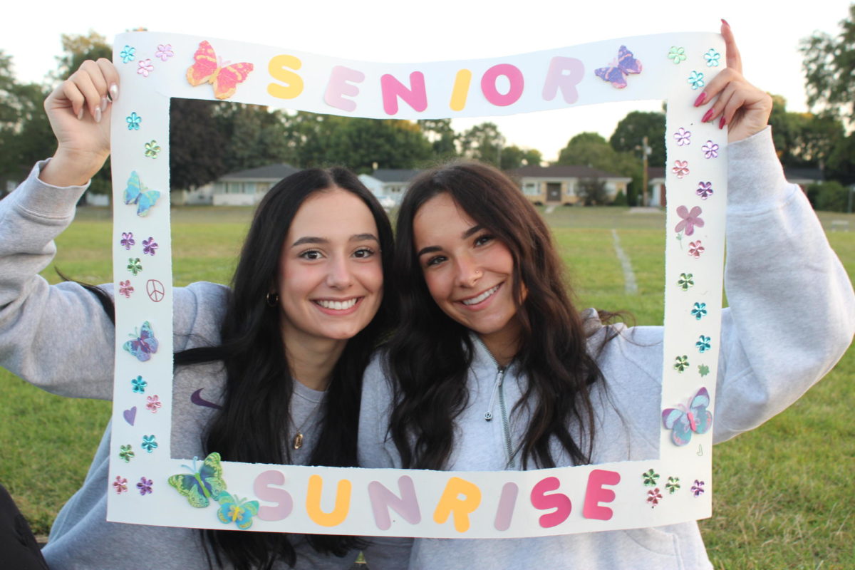 Ajla Majetic and Tina Ibricic, both seniors pose on the track field with a homemade Senior Sunrise frame, as they wait for the sun to rise.