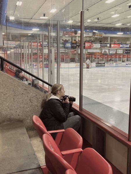 Junior, Jayna Gomez, captured taking photos at a Warriors hockey game.
