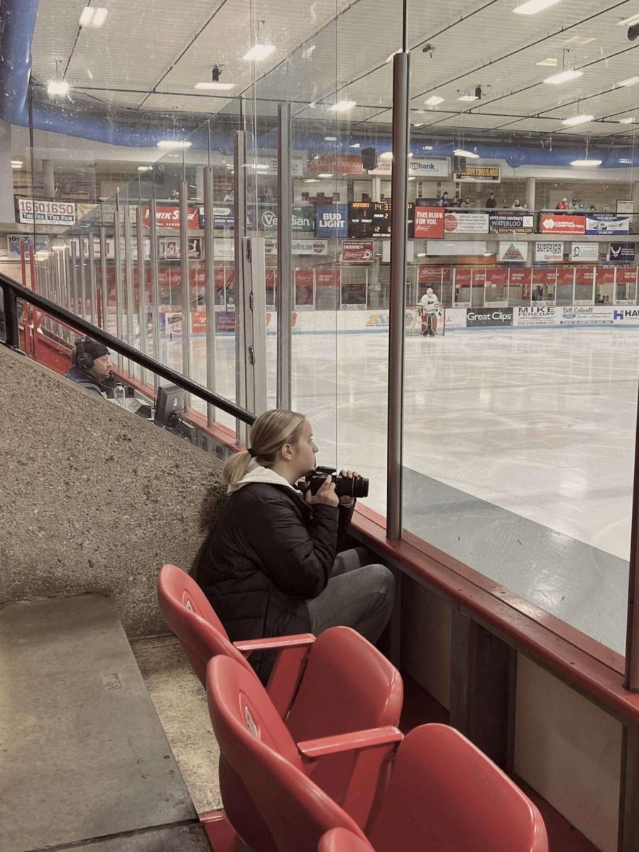 Junior, Jayna Gomez, captured taking photos at a Warriors hockey game.