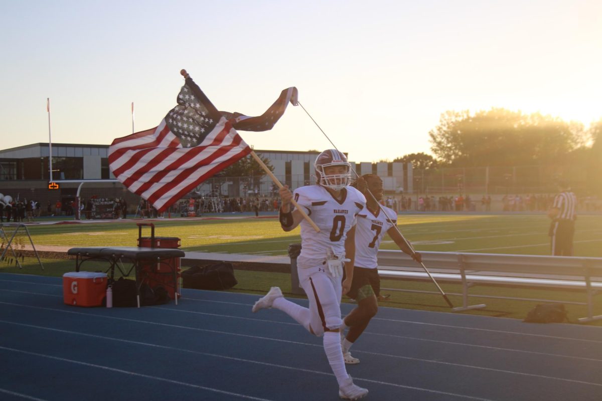 Seniors Nate Kline and Ben Frazier running onto the track with their flags.