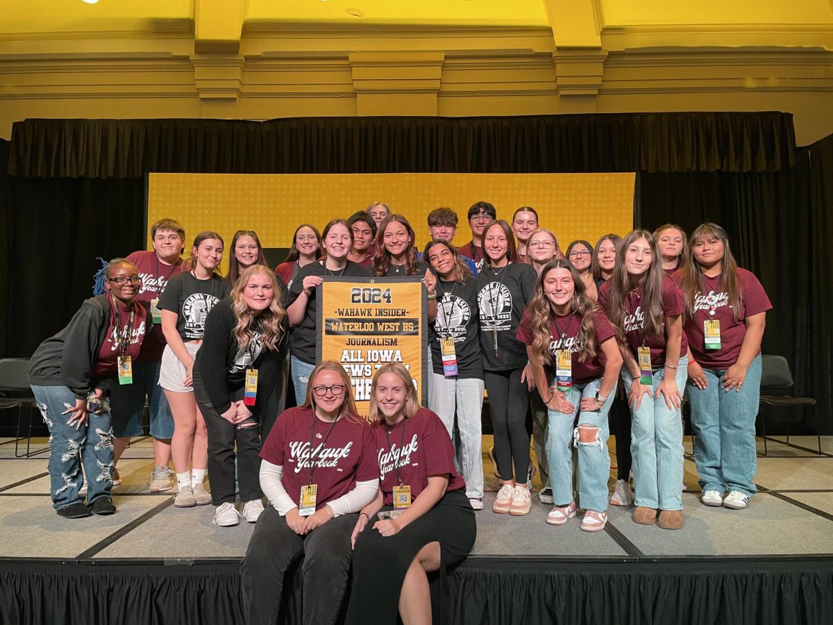 Wahawk Insider and Yearbook team posing for a photo with the News Team of the Year banner.