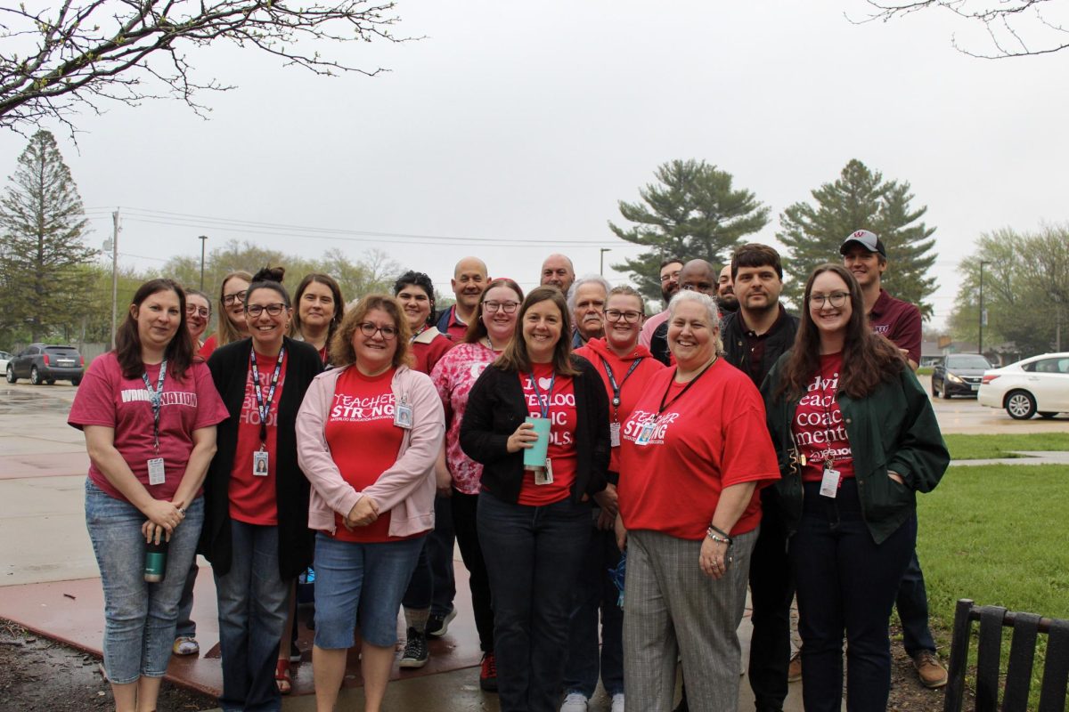 Waterloo West High teachers pose together for a photo before their May Day walk-in. These teachers all wore red to support public education as they enter the school building for their contract hours.