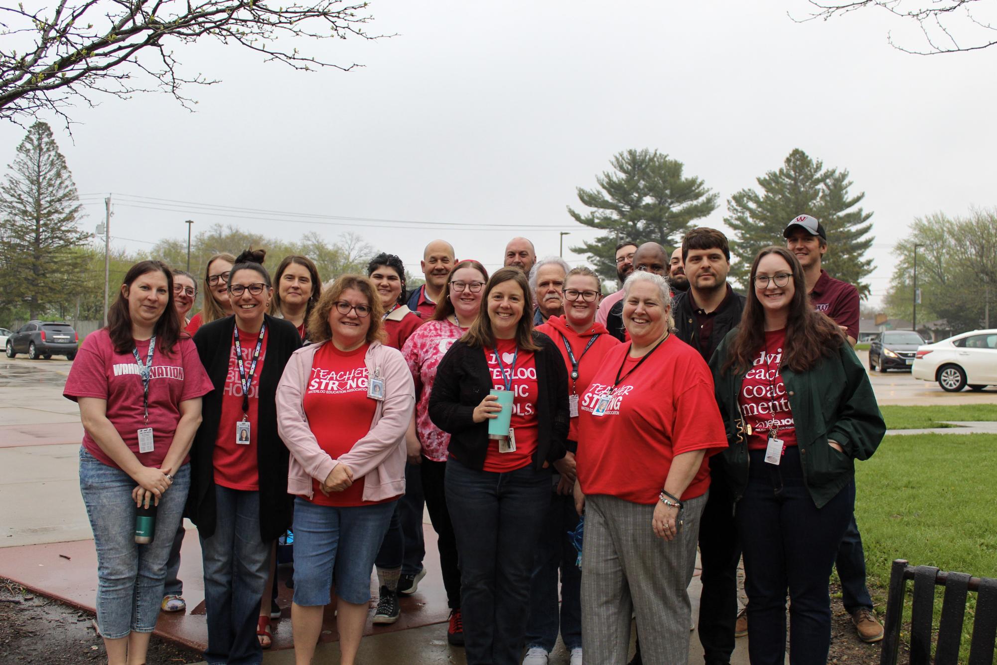 Waterloo West High teachers pose together for a photo before their May Day walk-in. These teachers all wore red to support public education as they enter the school building for their contract hours.