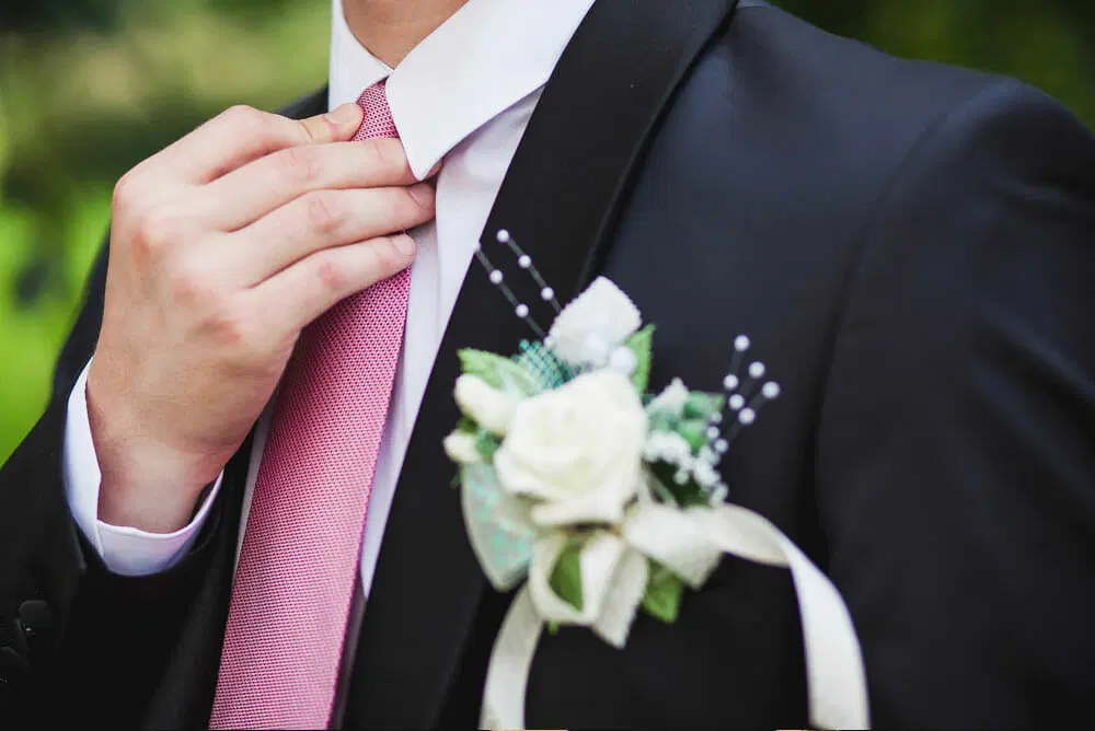 A teen boy adjusts his tie while he looks out into the distance. Many teenagers attend prom each year and it is looked forward to by many.