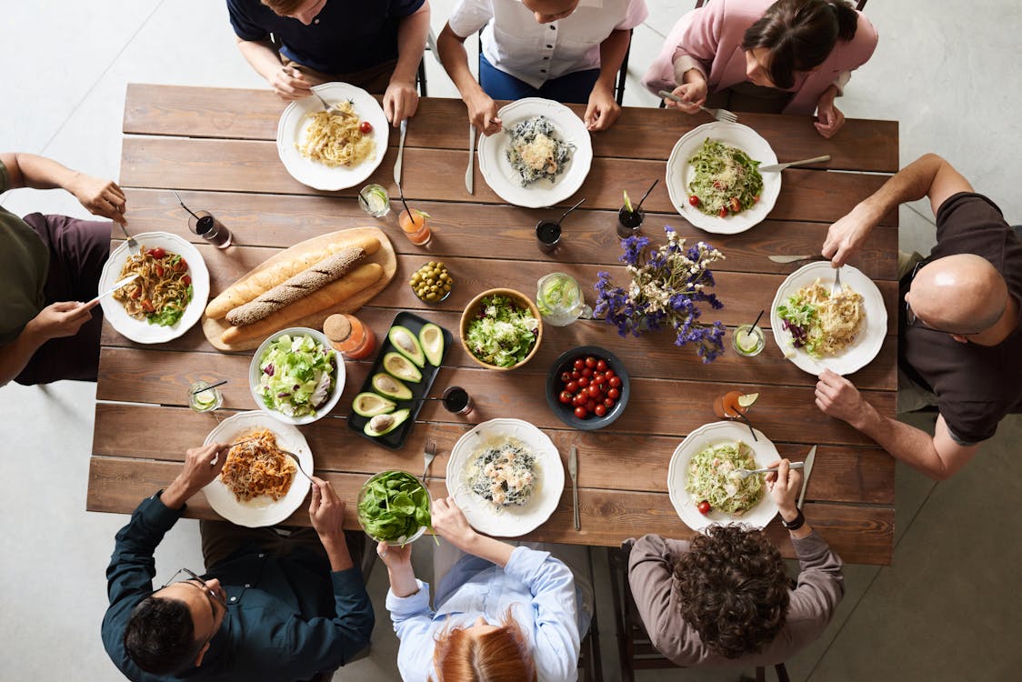 A group of friends sit down to eat a meal together. 
