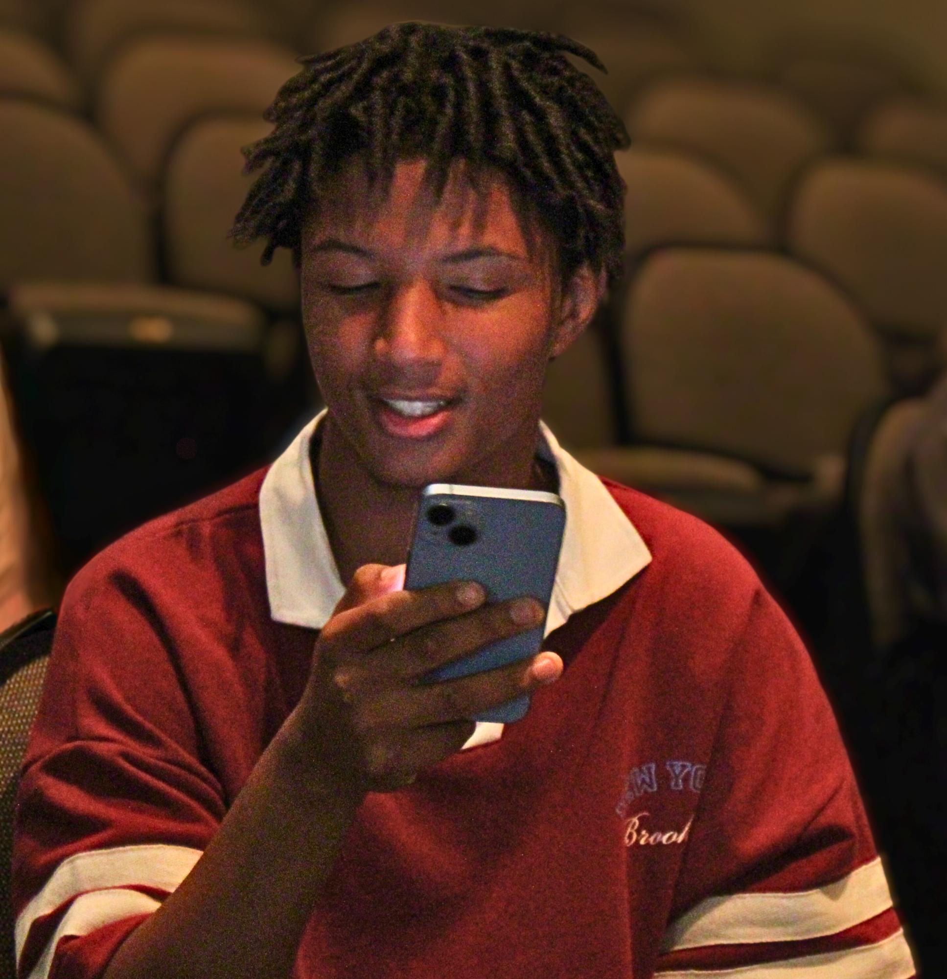 Senior Romeo Hill reads his script from his phone during a blocking rehearsal. 