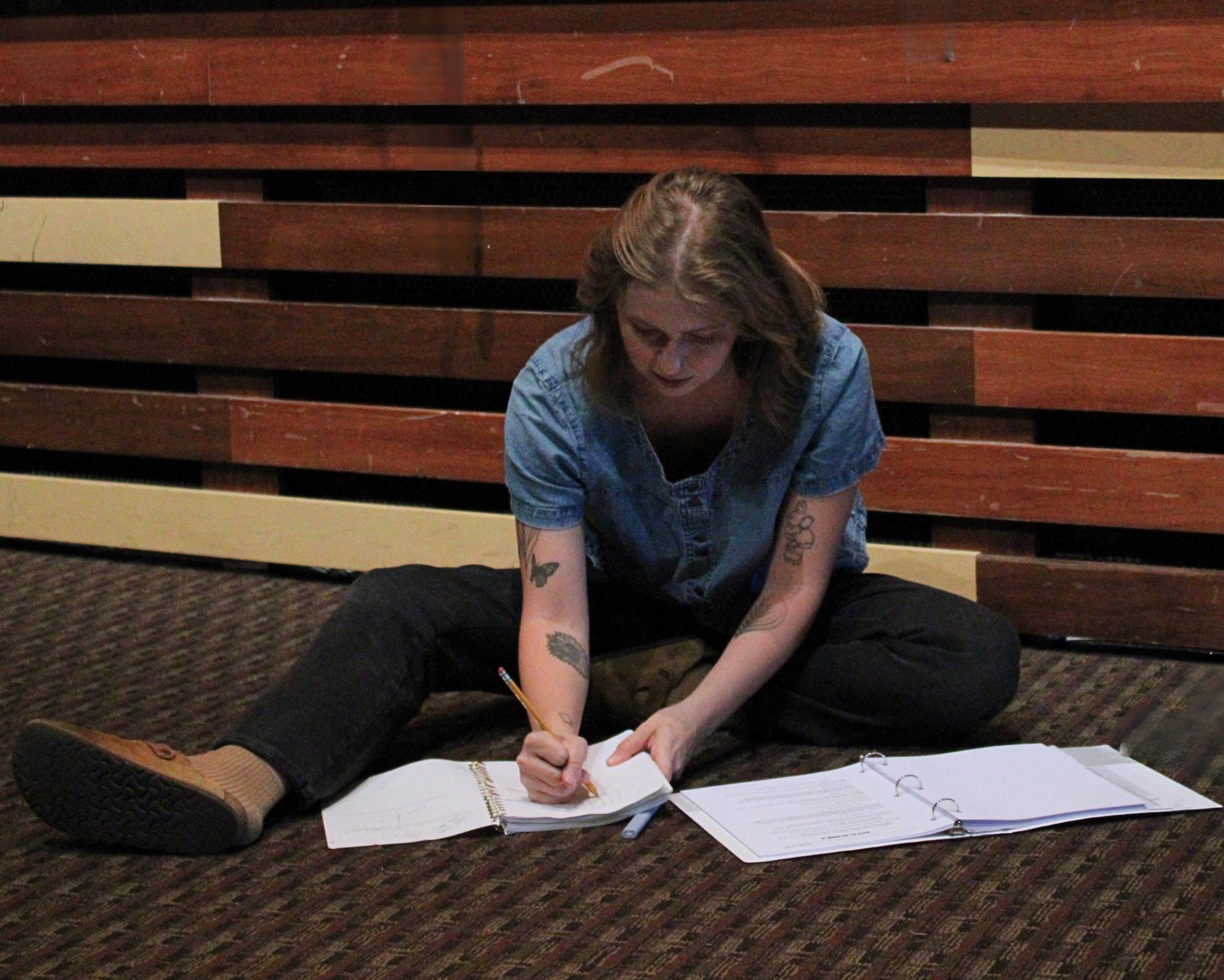 Assistant Director Regan Hirdler writes down notes for the blocking of a scene. She sits in rehearsal for The Legend of Sleepy Hollow.