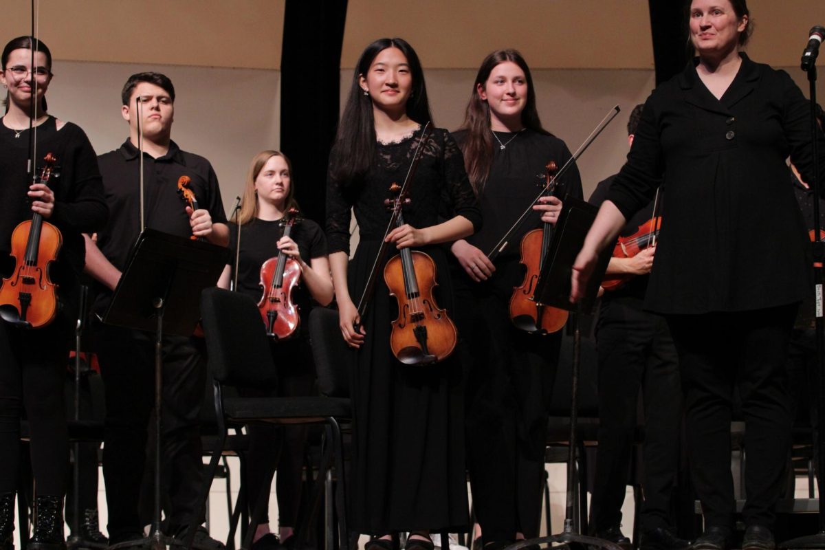 Senior Esther Shin stands proudly as the orchestra is introduced at an orchestra concert. 