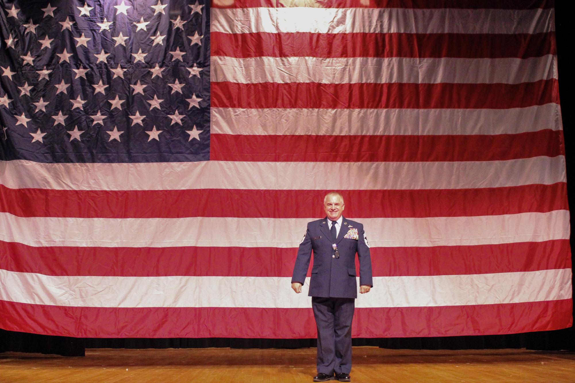 Chief Paul Wallace poses in front of the American flag following the Veteran's Day assembly in which he was a speaker. 