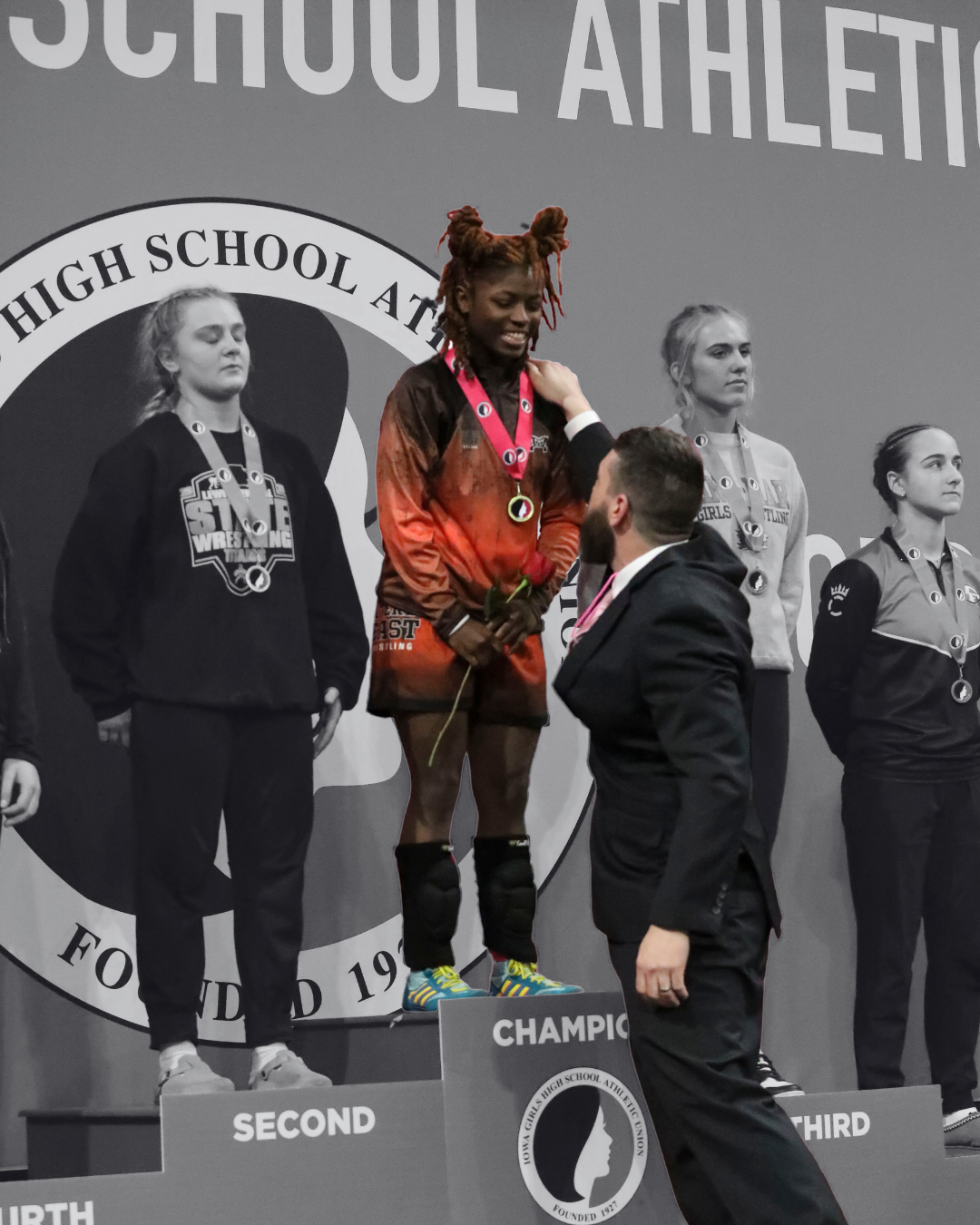 Daniesha Watson stands on the podium as head coach Josef Kadlec pats her on the shoulder after giving Watson her medal. 