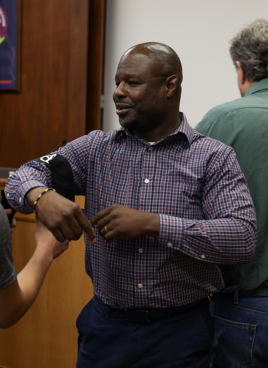 Board President Astor Williams smiles as he speaks with students who presented at the March 9 board meeting. Williams had the final say when it came to approving Zach O'Brien for his position. 