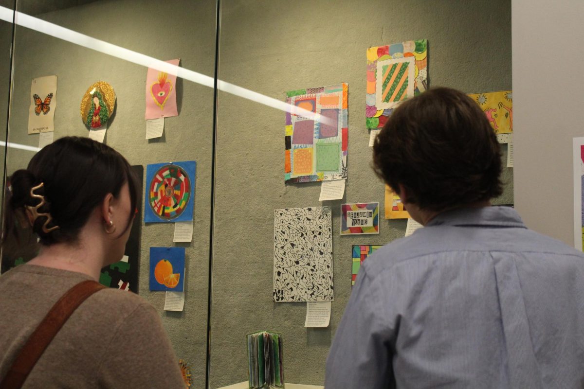 Senior Benjamin Young details his artwork to teacher Ms. Goodman during the IB Art Showcase.
