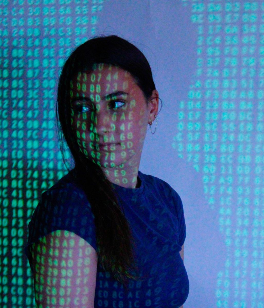 Junior Mackenzie Johnson looks over her shoulder as the numbers of technology cover her face.