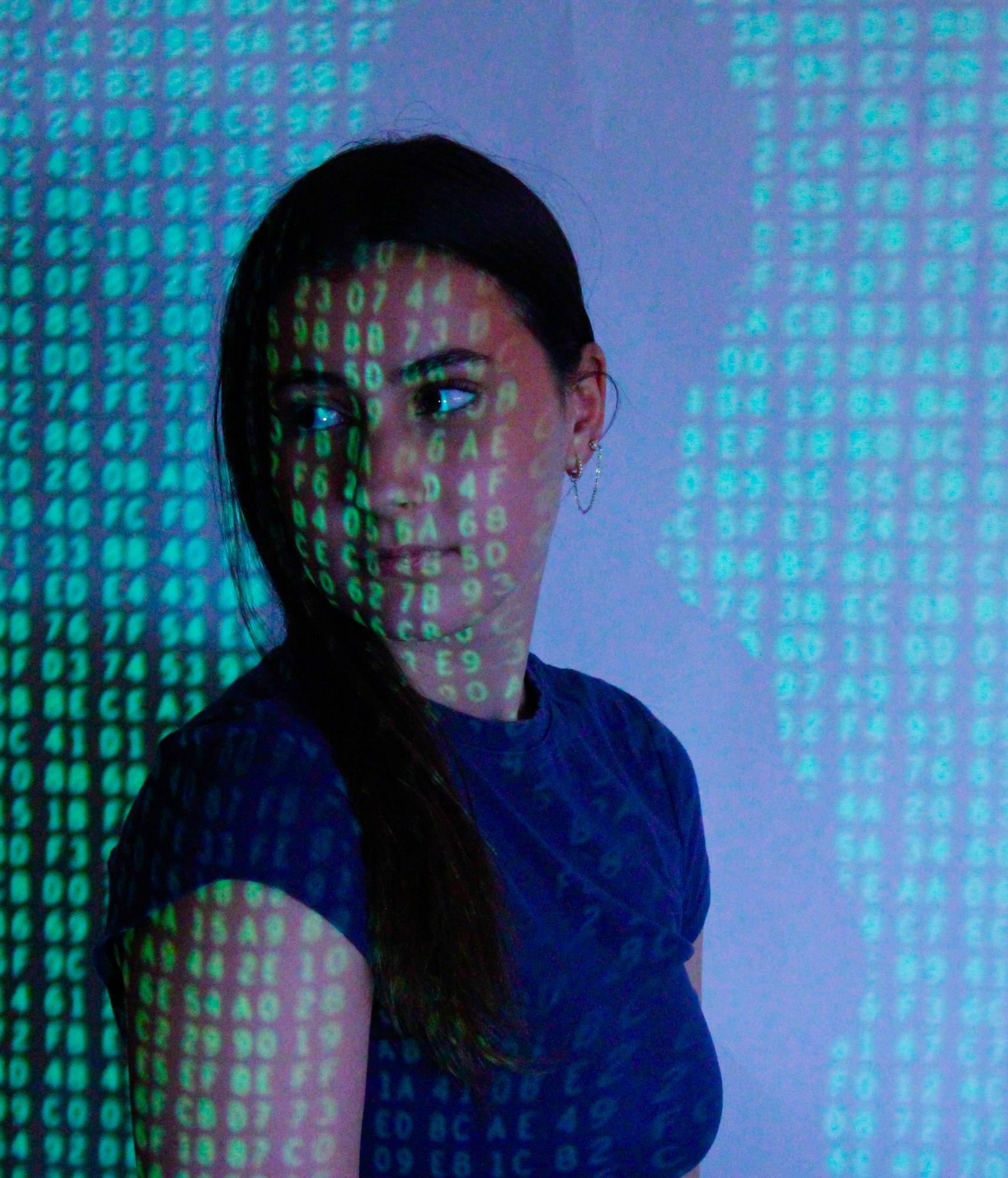 Junior Mackenzie Johnson looks over her shoulder as the numbers of technology cover her face.